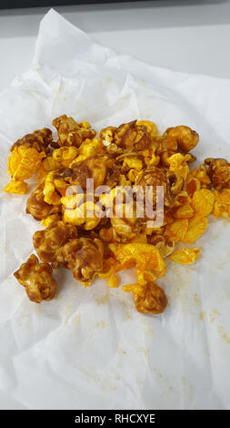 Caramel-flavored popcorn snacks on a tissue at the table Stock Photo