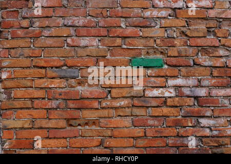 Blurred brick wall background. Brown brickwork wall with one green brick. Stock Photo