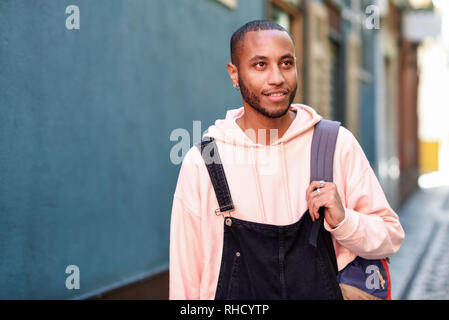 Young black man walking smiling down the street. 