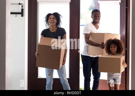 Excited black family entering new house holding boxes moving in Stock Photo