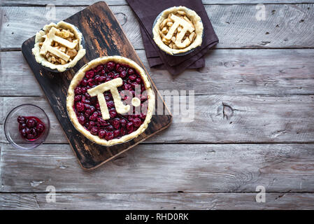 Pi Day Cherry and Apple Pies - making homemade traditional various Pies with Pi sign for March 14th holiday, on rustic wooden background, top view, co Stock Photo