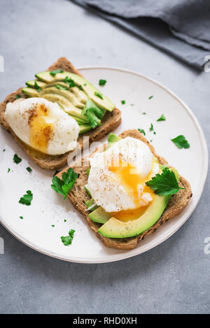 Avocado Sandwiches with Poached Eggs - sliced avocado and egg on toasted bread for healthy breakfast or snack. Stock Photo