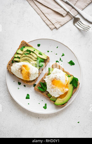 Avocado Sandwiches with Poached Eggs - sliced avocado and egg on toasted bread for healthy breakfast or snack. Stock Photo