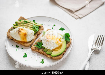 Avocado Sandwiches with Poached Eggs - sliced avocado and egg on toasted bread for healthy breakfast or snack. Stock Photo