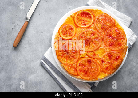Upside down orange cake on grey background, top view. Homemade cake with bloody oranges, citrus fruits. Stock Photo