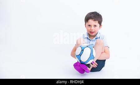 Portrait of the cute little boy playing football, isolated on studio white background. Adorable kid in sport activity, holding a soccer ball. Outdoor  Stock Photo