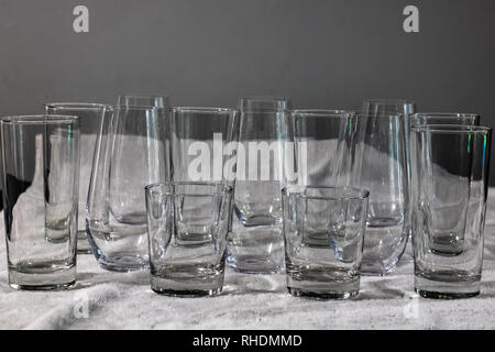 Interesting pattern of glass tumblers, tall, short, stemless, on a plain white towel. Stock Photo