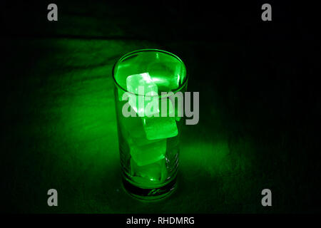 Ice cubes in a glass scattering light from a green laser pointer Stock Photo
