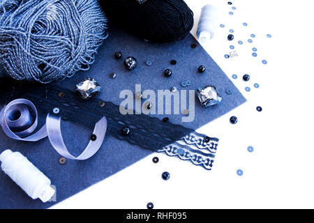 Materials for needlework in grey color on a white background. Beads, threads and wool for knitting Stock Photo