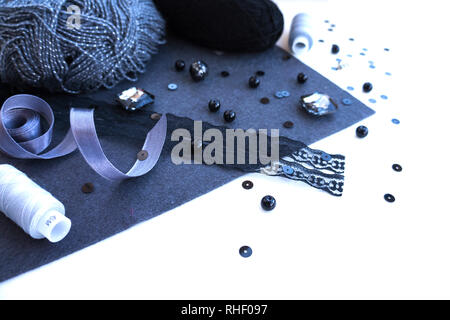 Materials for needlework in violet grey color on a white background. Beads, threads and ribbon. Stock Photo