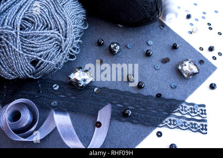 Materials for needlework in grey color on a white background. Beads, threads, a satin ribbon. Stock Photo