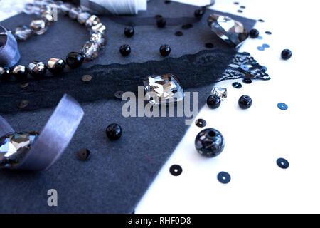A set of materials for needlework in violet grey color on a white background. Beads, threads and ribbon. Stock Photo