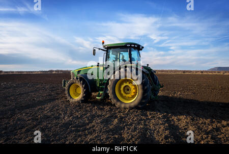 Varna, Bulgaria - March 5, 2017 Ploughing a field with John Deere tractor. John Deere was manufactured in 1995-1999 and it has JD 7.6L or 8.1L 6-cyl d Stock Photo