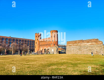 Turin, Italy - December 31, 2018. Aiuola Secondo Pia Park with the Parco Archeologico Torri Palatine and Porta Palatina Gate in the background. Piazza Stock Photo