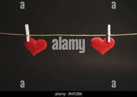 Two red hearts apart hanging from a string by white clothes peg. Valentine's Day or romantic occasion with copy space.