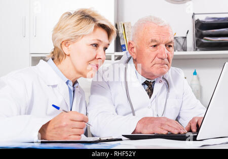 Mature male doctor and female nurse working effectively in office Stock Photo