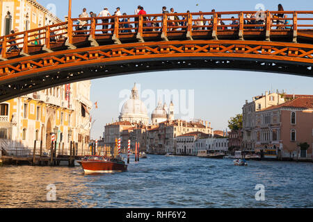 Accademia Bridge and Basilica di Santa Maria della Salute at sunset, Grand Canal, Venice, Veneto, Italy with water taxi sightseeing with tourists Stock Photo
