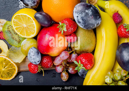 many different mixed seasonal ripe juicy fruits on dark background , concept of healthy and proper nutrition, snack, top view, copy space Stock Photo