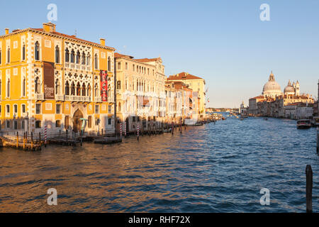 Grand Canal at sunset with a view past Palazzo Cavalli-Franchetti  to Basilica di Santa Maria della Salute with boat traffic, Venice, Veneto, Italy Stock Photo