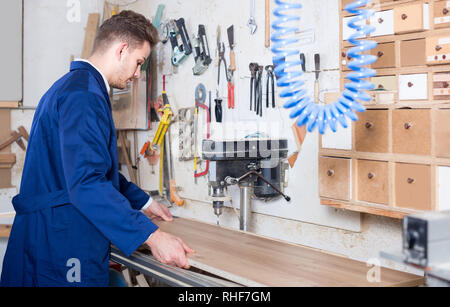 Young smiling american guy using drilling machine at workshop Stock Photo