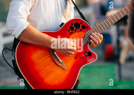 A man plays a guitar dressed in a white shirt. Stock Photo