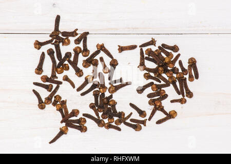 Lot of whole small dried cloves spice flatlay on white wood Stock Photo
