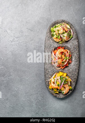 CEVICHE. Three colorful shrimps ceviche with mango, avocado and tomatoes. Latin American Mexican Peruvian Ecuadorian food. Served with white wine and Stock Photo