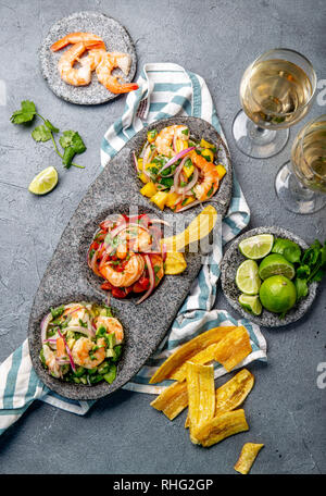 CEVICHE. Three colorful shrimps ceviche with mango, avocado and tomatoes. Latin American Mexican Peruvian Ecuadorian food. Served with white wine and Stock Photo