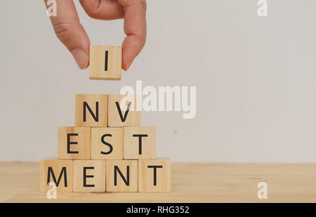man hand try to put or complete the investment cube wood Stock Photo