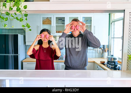 Lovely couple posing - covering they're eyes with the pink eggs and making a face Stock Photo