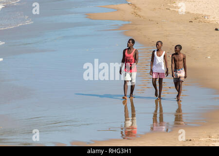 Durban, South Africa - January 7th, 2019: Three south african black men walking alone in the beach looking at the sea in a beach in Durban, South afri Stock Photo