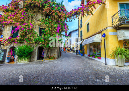 SIRMIONE, ITALY - AUGUST 28, 2017: Amazing colorful purple bougainvillea flowers around the windows. Spectacular mediterranean promenade with souvenir Stock Photo