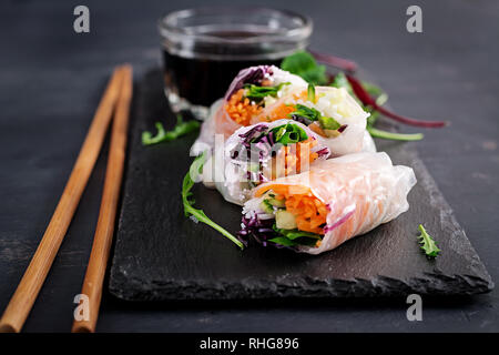 Vegetarian vietnamese spring rolls with spicy sauce, carrot, cucumber, red cabbage and rice noodle. Vegan food. Tasty meal.  Copy space Stock Photo