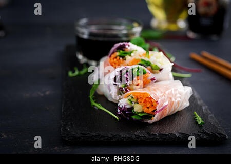 Vegetarian vietnamese spring rolls with spicy sauce, carrot, cucumber, red cabbage and rice noodle. Vegan food. Tasty meal.  Copy space Stock Photo