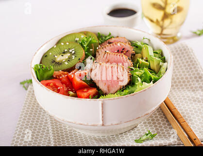 Salad. Poke bowl. Buddha bowl. Traditional salad with pieces of medium-rare grilled Ahi tuna and sesame with fresh vegetables and rice on a plate. Top Stock Photo