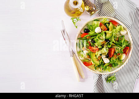 Fresh salad with avocado, tomato, olives and mozzarella  in a  bowl.  Fitness food. Vegetarian meal. Top view Stock Photo