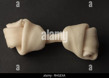 One white leather rawhide dog chew toy on dark gray background Stock Photo