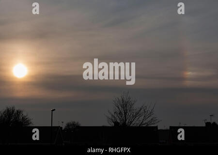 Sun setting over silhouetted rooftops Stock Photo