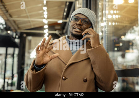 Dark-eyed businessman speaking on the phone with his colleague Stock Photo