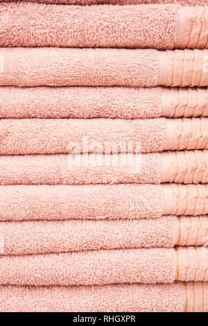 Stack of clean pink cotton towels, vertical shot, towel textured background Stock Photo