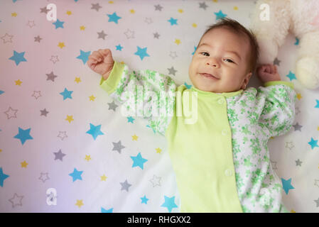 Smiling baby girl  laying on bed above top view Stock Photo