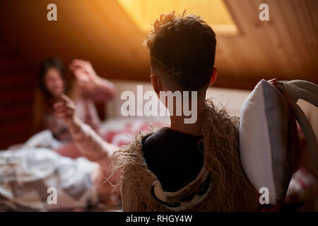Mom and son play on the bed, in the morning arrange a pillow fight in their pajamas Stock Photo