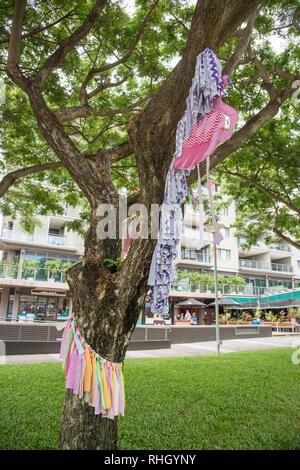 Darwin, Northern Territory, Australia-October 27,2017:  Fabric art installation on a tree trunk at the waterfront with tourists in Darwin, Australia Stock Photo