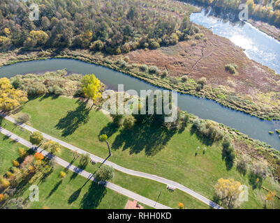 natural landscape aerial top view. city park with bushy autumnal trees, green lawns, bikeway and river Stock Photo