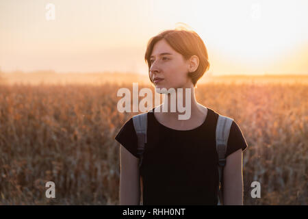 Backlit portrait of a woman in sunset. Female person standing in evening sunlight at a field Stock Photo
