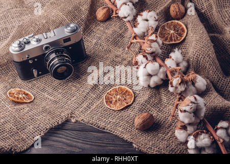 Old retro camera on a table with burlap and cotton on a sprig Stock Photo