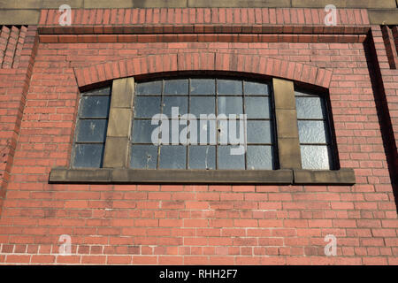Red brick wall on industrial building, with arched window and stone lintel in bury lancashire uk Stock Photo