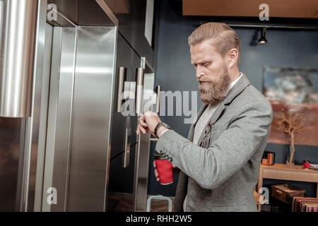 Concentrated young male waiting elevator in hall Stock Photo