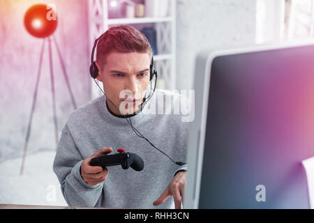 Modern teenager feeling amazing while playing his favorite computer game Stock Photo