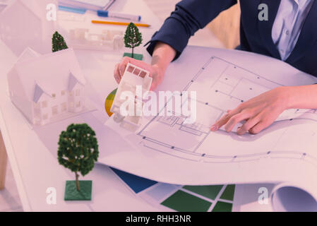 Young woman comparing house model with blueprint Stock Photo